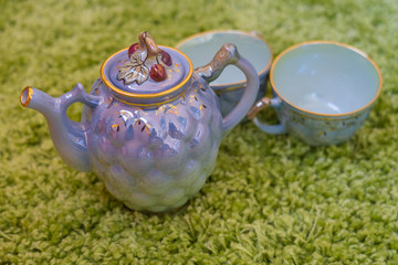 Closeup view of colorful ceramic vintage tea set standing on green carpet