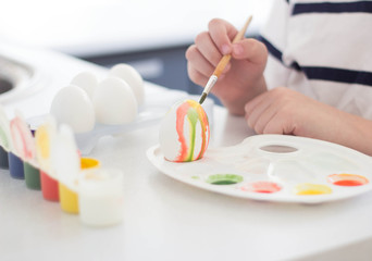 a child paints eggs with watercolors and gouache waits for Easter and plays