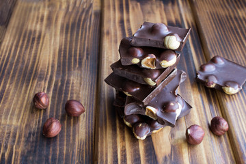 Pieces of dark chocolate with hazelnuts on the brown wooden  background. Closeup.