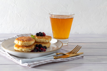 Homemade pancakes with cottage cheese on a white lantern with black currants and cranberries. Breakfast for the whole family. Healthy vegan food concept.