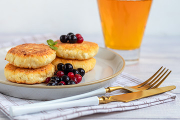 Homemade pancakes with cottage cheese on a white lantern with black currants and cranberries. Breakfast for the whole family. Healthy vegan food concept.