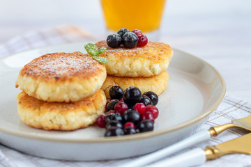 Homemade pancakes with cottage cheese on a white lantern with black currants and cranberries. Breakfast for the whole family. Healthy vegan food concept.