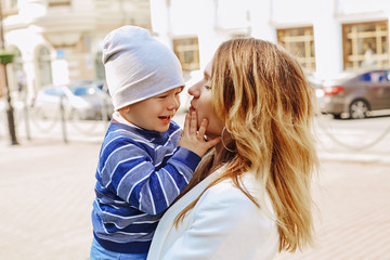 A small child in her arms smiles while walking. Walk the streets of the city in good flying weather. Sunny day.