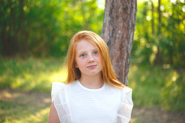 red-haired girl in a white dress walks in the park