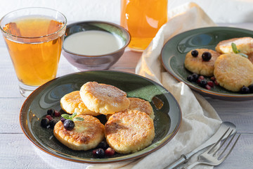 Homemade pancakes with cottage cheese on a white lantern with black currants and cranberries. Breakfast for the whole family. Healthy vegan food concept.