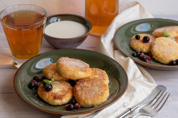 Homemade pancakes with cottage cheese on a white lantern with black currants and cranberries. Breakfast for the whole family. Healthy vegan food concept.
