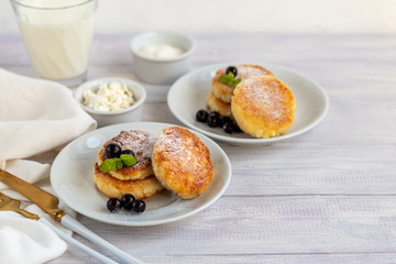 Homemade pancakes with cottage cheese on a white lantern with black currants and cranberries. Breakfast for the whole family. Healthy vegan food concept.