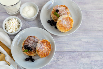 Homemade pancakes with cottage cheese on a white lantern with black currants and cranberries. Breakfast for the whole family. Healthy vegan food concept.