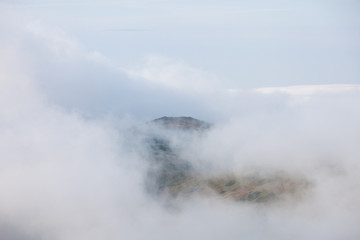 Mountain range through clouds and fog at stormy summer day