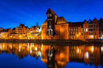 Fototapeta premium Old town in Gdansk with historical port crane over Motlawa river at night, Poland.