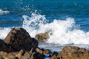 Ocean wave splashing over rocks closeup