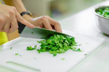 Cook in the kitchen cuts greens close up