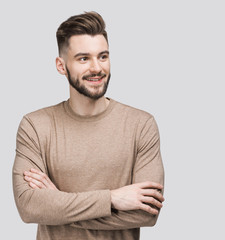Fototapeta premium Portrait of handsome smiling young man with folded arms. Smiling joyful cheerful men with crossed hands studio shot. Isolated on gray background