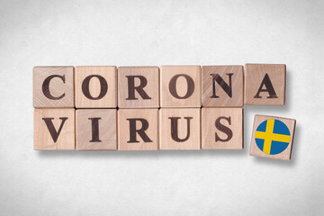 Wooden blocks with flag of Sweden and letters spelling CORONAVIRUS on white paper texture background. Novel Coronavirus (2019-nCoV) concept, for an outbreak occurs in Sweden.