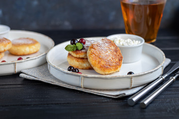 Homemade pancakes with cottage cheese on a dark lantern with black currants and cranberries. Breakfast for the whole family. Healthy vegan food concept.