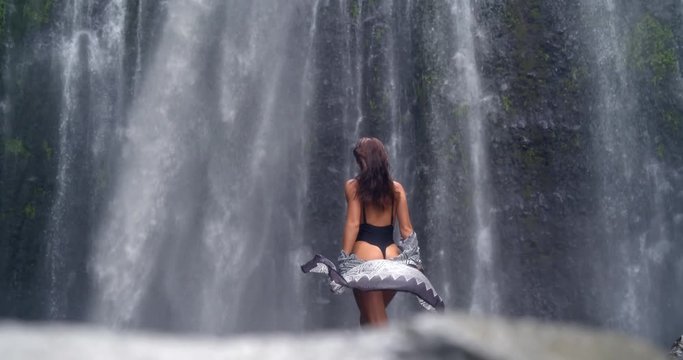 back view of breathtaking young model posing at mountain waterfall, amazing scenery of tropical jungle wildlife