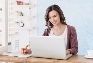 Cheerful woman using laptop at home, Young girl working on computer, Blogger, writer, journalist or...