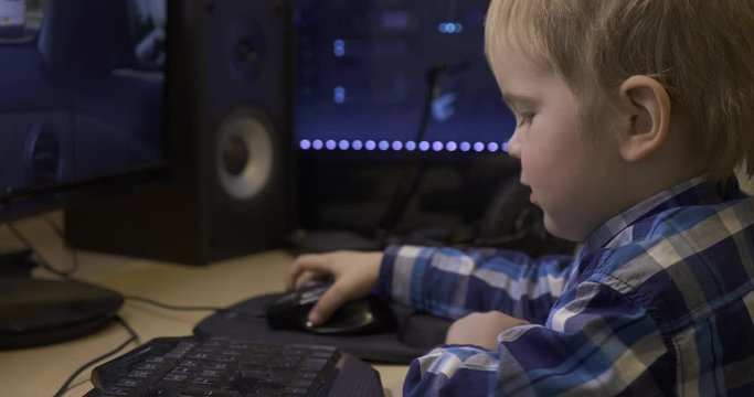 Little Child Learning How to Use Computer Mouse Surfing Internet Playing Watching PC. Boy Sits in Front of Green Screen Monitors. Father's Editing PC Workstation. Gaming PC. 10 bit HLG
