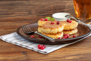 Homemade pancakes with cottage cheese on a wooden lantern with black currants and cranberries. Breakfast for the whole family. Healthy vegan food concept.