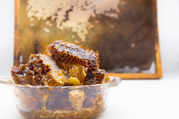 Natural honey lies in a glass plate. Natural honey in the frame in the background.