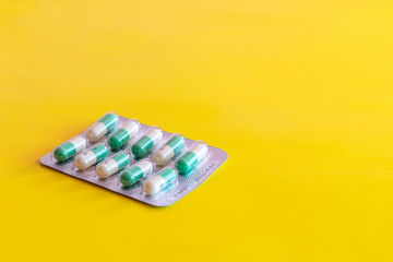 One blister of antidepressant pills on yellow background.Generic tablets.Oval green and white capsules in package.No people and copy space.Mental health issue.Depression treatment.Healthcare, medicine