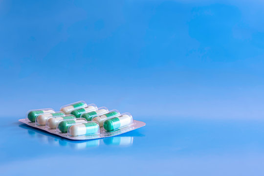 One blister of antidepressant pills on blue glossy background.Generic package of oval, white and green tablets.No people and copy space.Depression treatment.Mental health.Prescription medication.