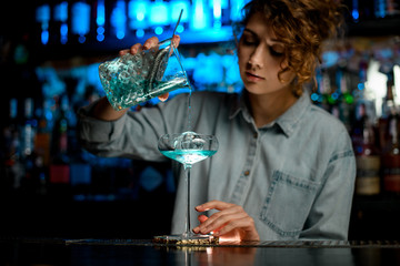 pretty woman bartender accurate pour cocktail into glass