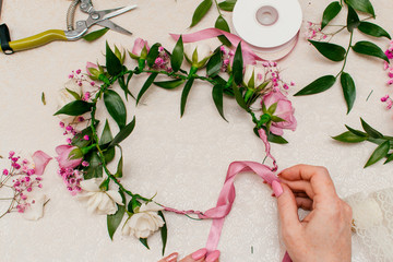 The process of making a bride's wedding wreath from fresh flowers of cream and pink rose,gypsophila and Ruskus leaves.Step-by-step instruction, step 16, top view