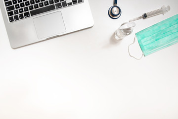 Top view of medical gear, mask, sanitizer, stethoscope and laptop during epidemic virus