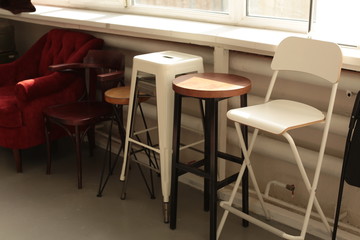 various different chairs stools stand along the wall by the window