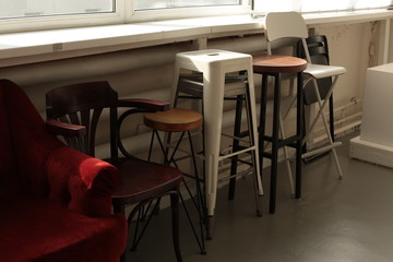 various different chairs stools stand along the wall by the window