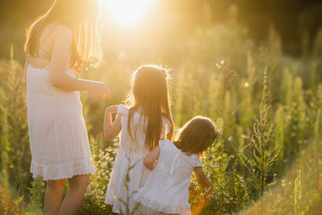 happy family walks in nature. Mom throw their children. Mom and two daughter 