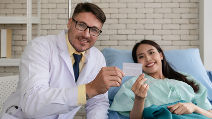 Obraz premium health insurance card in hands of doctor and patient that having thumb up together showing benefit of having health insurance when getting sick or having accident, selective focused