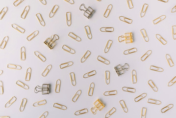 Set of silver and gold paper clips on light grey background. Flat lay. Office and business concept.