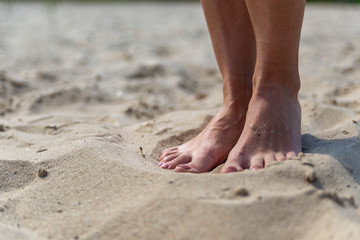 Obraz na płótnie Canvas female feet on sand at beach in summer in sunny weather