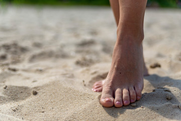 Obraz na płótnie Canvas female feet on sand at beach in summer in sunny weather
