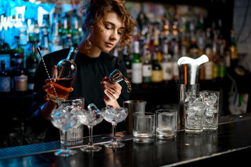 bartender lady accurate pours drink into metal glass using jigger
