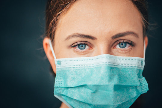 Protection against contagious disease, coronavirus. Female doctor wearing hygienic face surgical medical mask to prevent infection, respiratory illness as flu, 2019-nCoV. Studio photo black background