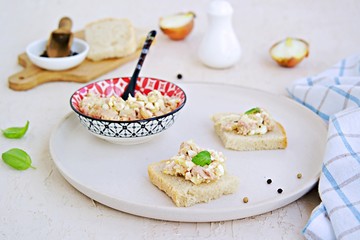 Appetizer, salad of canned cod liver, boiled egg and onion on slices of fresh white bread on a light ceramic tray. Appetizer Recipes