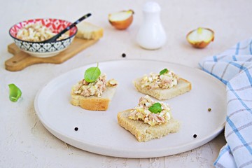 Appetizer, salad of canned cod liver, boiled egg and onion on slices of fresh white bread on a light ceramic tray. Appetizer Recipes