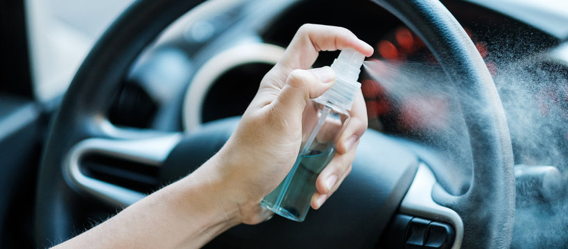 man hand spraying alcohol sanitizer on steering wheel in his car, against Novel coronavirus or Corona Virus Disease (Covid-19). Antiseptic, Hygiene and Healthcare concept