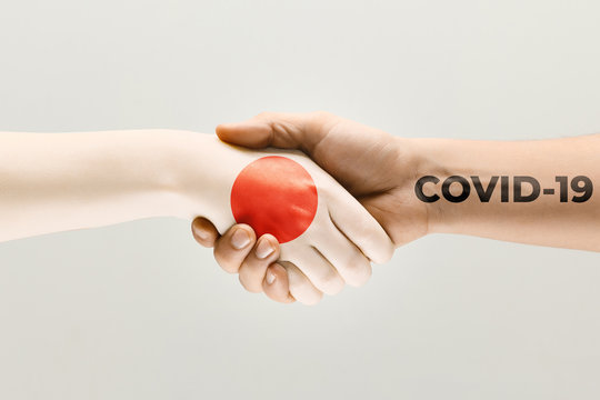 Human hands colored in flag of Japan and coronavirus - concept of spreading of virus. Hands shaking is danger, the way of wordwide epidemic. Stay safe. Prevention, safety, pandemic spread concept.