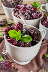 Homemade chocolate mug cake with blackberry. Breakfast easy snack recipe, chocolate non dairy cake in mugs, with blackberry, sugar powder and mint, wooden rustic background