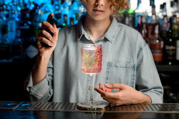 Decorated glass with pink drink stands at the bar.