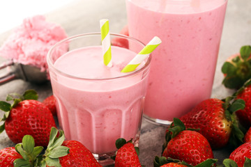 Glass of fresh strawberry shake, smoothie or milkshake and fresh strawberries on table. Healthy...
