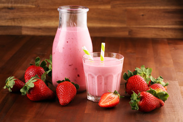 Glass of fresh strawberry shake, smoothie or milkshake and fresh strawberries on table. Healthy food and drink concept