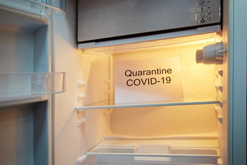 The refrigerator is empty without food, a plate with the inscription Quarantine COVID-19