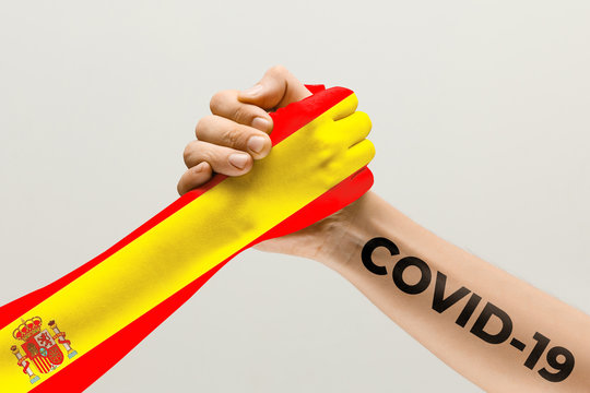 Human hands colored in flag of Spain and coronavirus - concept of spreading of virus. Hands shaking is danger, the way of wordwide epidemic. Stay safe. Prevention, safety, pandemic spread concept.