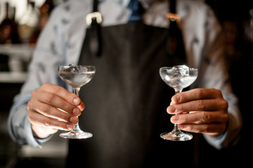bartender's hands holding two glasses with ice