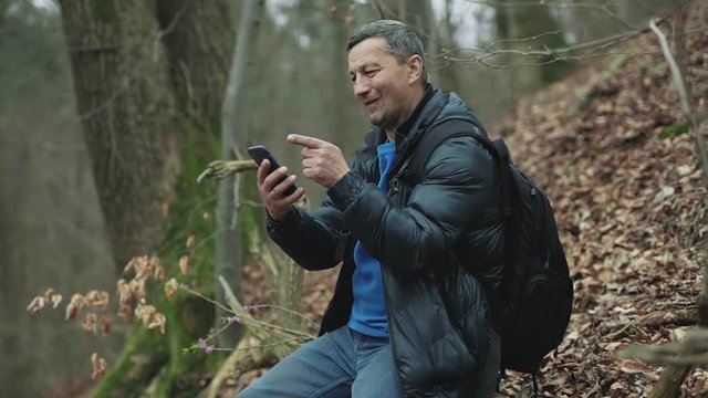 Shot of man uses smarphone in the spring forest smile feel happy technology park cellphone autumn traveller tree telephone mobile phone casual close up slow motion